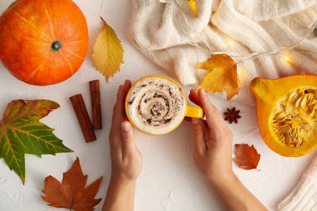 Composición con manos femeninas sostienen latte de calabaza