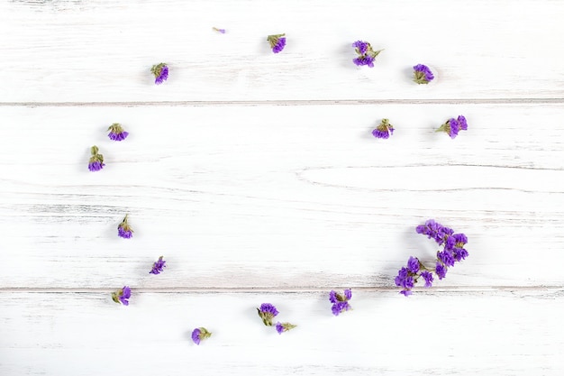 Composición de marco de flores violetas sobre un fondo de madera blanco rústico