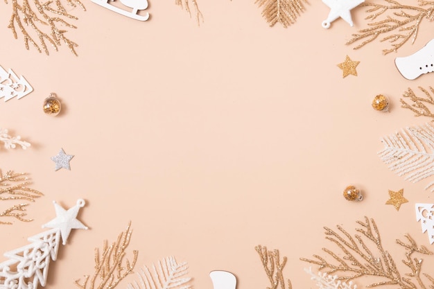 Composición de marco de navidad o año nuevo adornos navideños en colores dorados sobre fondo beige pastel con espacio de copia vacío para saludar