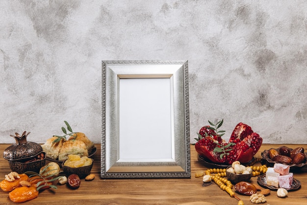 Composición para el marco Ramadan Silver con espacio para copiar o maqueta cerca de la vajilla islámica tradicional con comida en una mesa de madera