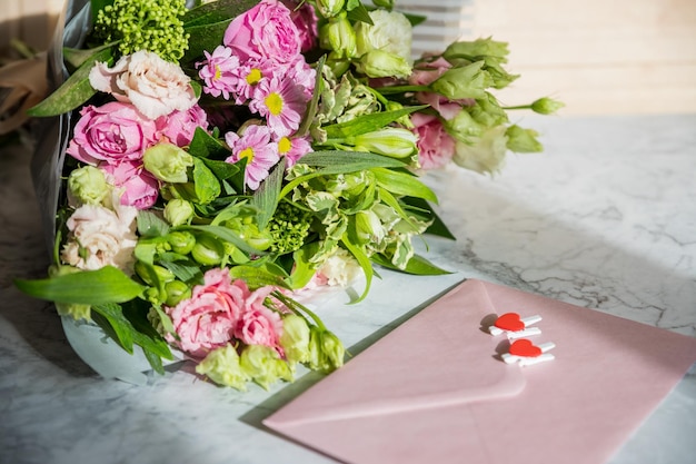 Foto composición de marco con ramo con sobre de eustoma de rosas y corazón rojo elementos decorativos florales sobre fondo de mármolfeliz día de la mujer feliz día de la madre concepto de día de san valentín