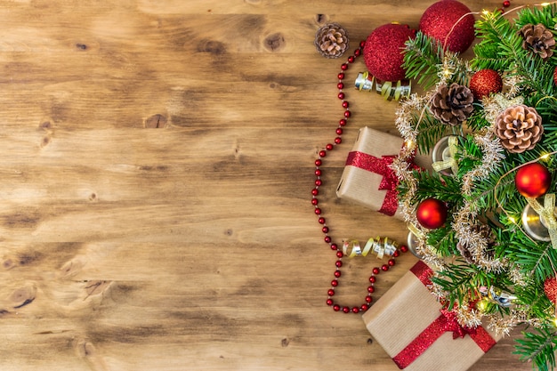 Composición de la mesa de Navidad para sus mensajes de vacaciones de invierno. Árbol de Navidad, regalos, piñas, bolas de Navidad, luces de Navidad y estrellas en una bonita madera marrón.