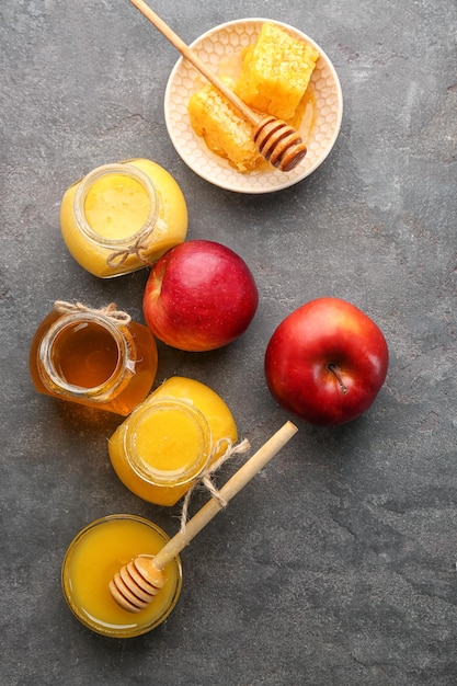 Foto composición con miel aromática y fruta sobre mesa gris.