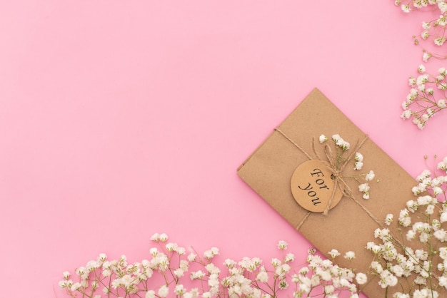 Composición mínima con un sobre rosa, una tarjeta blanca en blanco y una flor de cera.