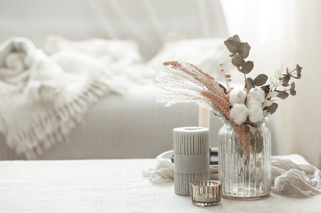 Una composición minimalista al estilo escandinavo con flores secas en un jarrón y velas.
