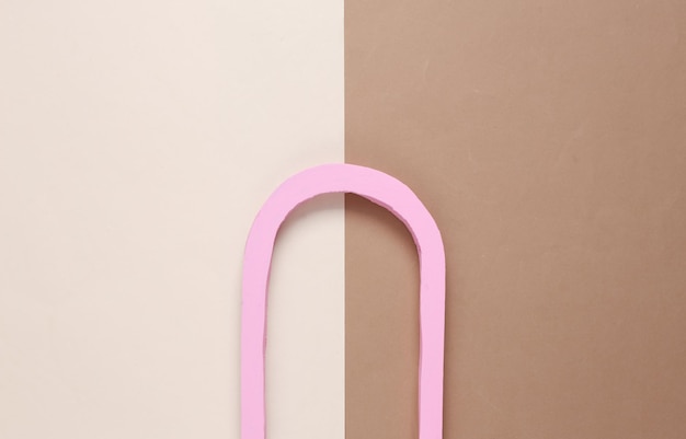 Composición minimalista de un arco rosa sobre un fondo marrón beige