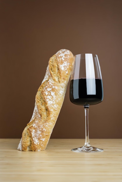 Foto composición minimalista de una copa de vino tinto y una baguette