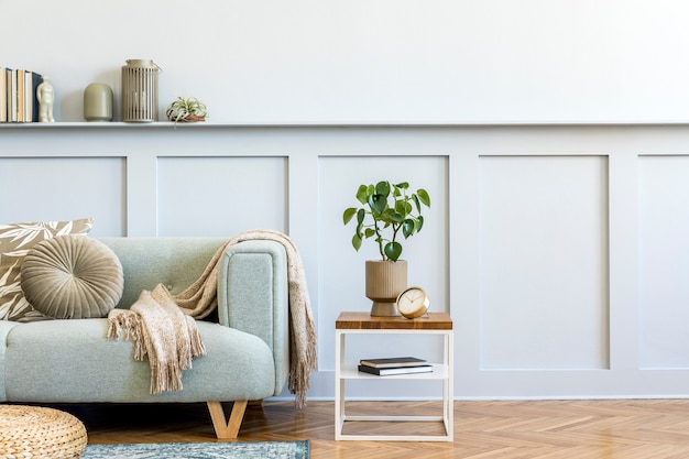 Composición minimalista de sala de estar con sofá de diseño, mesa de café, plantas, libros, decoración, almohadas, cuadros, alfombras, paneles de madera y elegantes accesorios personales en una decoración elegante para el hogar.