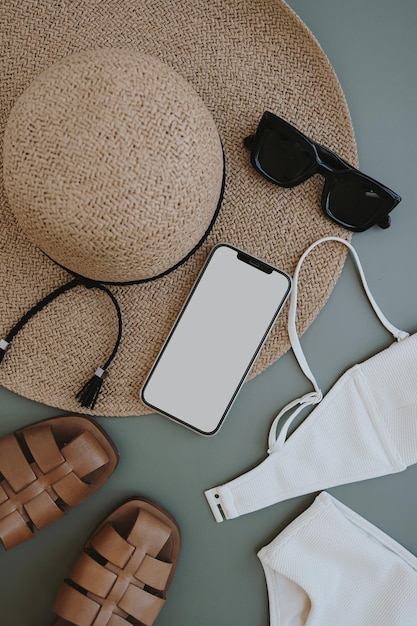 Composición de moda femenina de verano con sombrero de paja gafas de sol sandalias en fondo pastel teléfono inteligente con pantalla de espacio de copia ropa de vista superior plana concepto de compras de blog de moda femenino