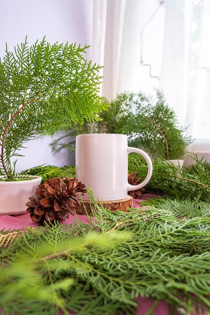 La composición muestra el producto. Taza blanca en madera redonda vieja con decoración de hojas de abeto. ideas de exhibición de productos de verano