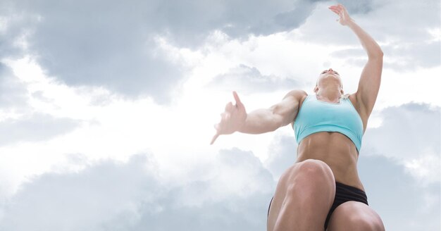 Composición de mujer atlética saltando sobre el cielo con nubes