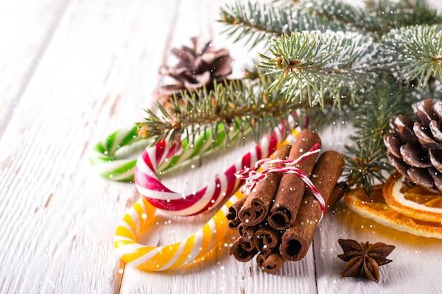 Composición de Navidad con bastones de caramelo y palitos de canela sobre fondo blanco de madera