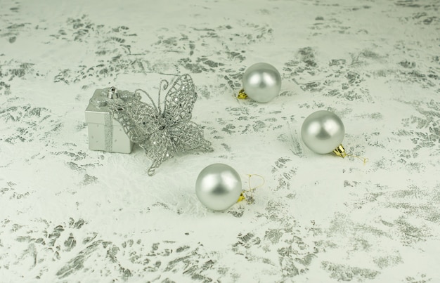 Composición de Navidad en el fondo blanco original de Año Nuevo. Caja regalo plateada -juguete, mariposa brillante calada y bolas plateadas.