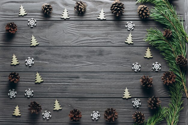 Composición de Navidad: fondo gris de madera con conos de pino, abeto, pequeño árbol de madera verde y copos de nieve. Vista superior con espacio libre para texto. Foto de naturaleza muerta. Navidad y concepto de año nuevo.