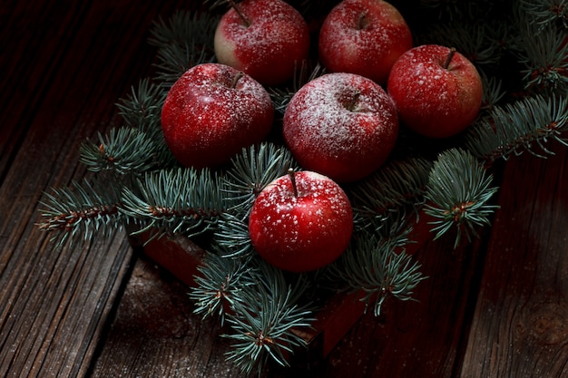 Composición de Navidad con manzanas rojas nevadas y ramas de abeto verde