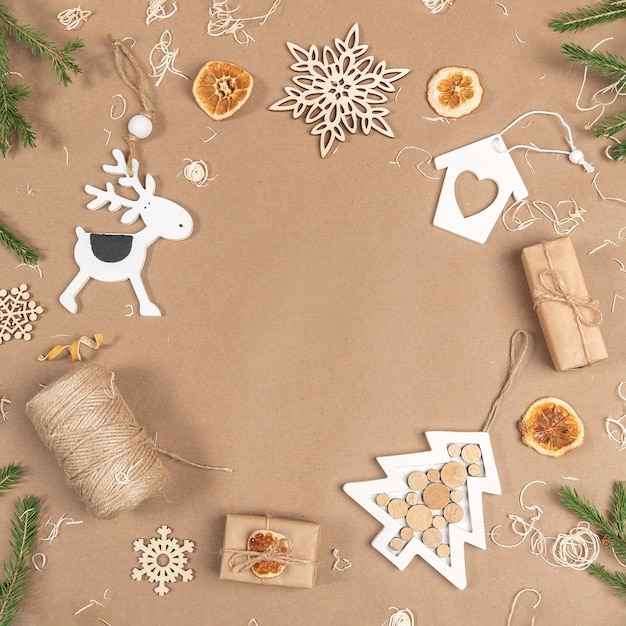 Composición de Navidad o año nuevo. Marco, borde de cajas, cordeles, decoración de madera, naranjas secas y ramas de abeto sobre fondo beige artesanal. Concepto Cero residuos Feliz Navidad Copie el espacio.