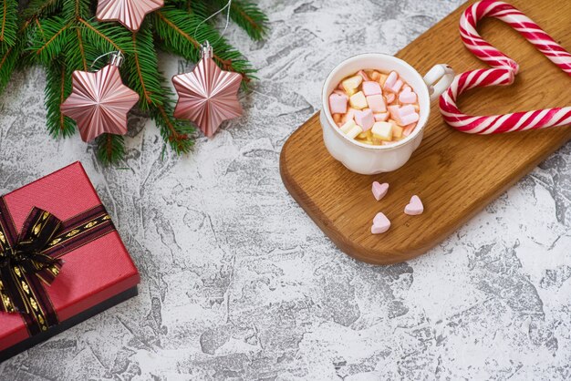 Composición de Navidad o año nuevo de marshmellow cup en soporte de madera, ramas de abeto verde, regalo, estrellas y piruletas