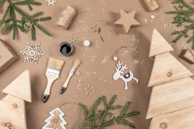 Composición de Navidad o Año Nuevo Árboles de Navidad de madera Pinceles y ramas de abeto sobre fondo beige artesanal Concepto Cero desperdicio ecológico Feliz Navidad Vista superior Lay Flat