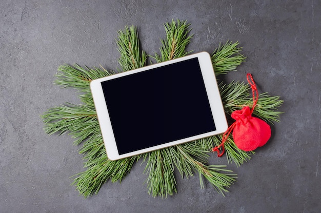 Composición de Navidad o año nuevo sobre un fondo de hormigón oscuro. Ramas de pino y una tablilla para saludos. Endecha plana, vista superior, espacio de copia.