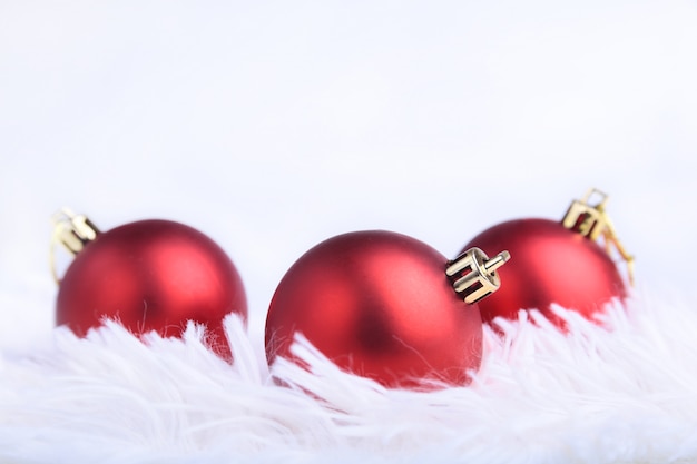 Foto composición de navidad o vacaciones con bolas de plata rojas sobre plumas ondulantes con nieve y copos de nieve.