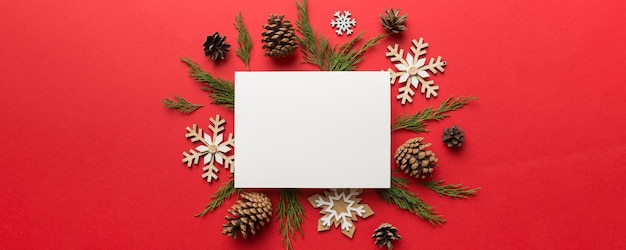 Composición de Navidad plana cuadrada papel en blanco ramas de pino decoraciones navideñas en fondo de color vista superior espacio de copia para el texto