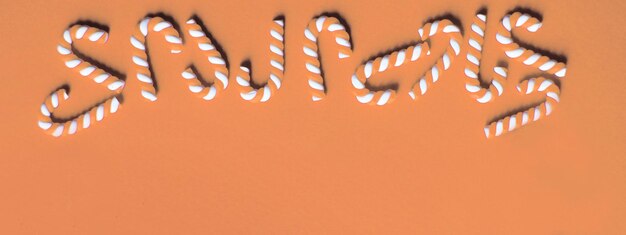 Composición de Navidad plana con marco de bastones de caramelo en un fondo de Peach Fuzz Copiar espacio para el texto Color del año 2024