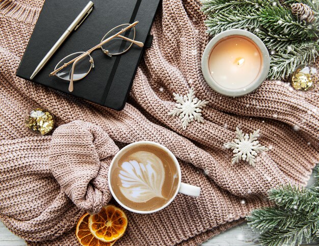 Composición de Navidad plana con una taza de decoraciones de velas de café y un abeto en un suéter de punto