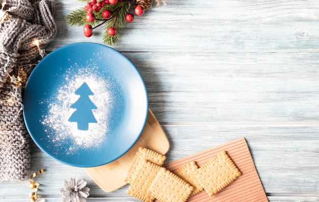 Composición de Navidad, plato, galletas y adornos navideños sobre un fondo de madera