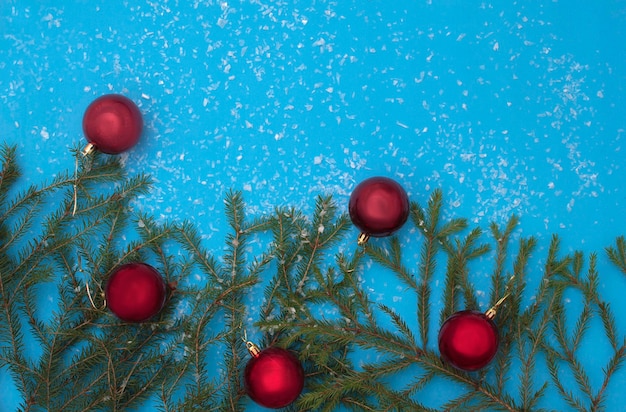 Una composición de Navidad sobre un fondo azul, un marco de ramas de árboles de Navidad y juguetes de árboles de Navidad en el fondo están aislados en un fondo blanco. Espacio para texto.