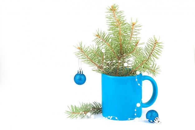 Composición de Navidad en una taza de té azul, ramas de abeto, bolas. Color azul clásico