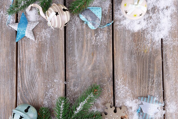 Foto composición navideña con abeto, juguetes y nieve sobre fondo de madera