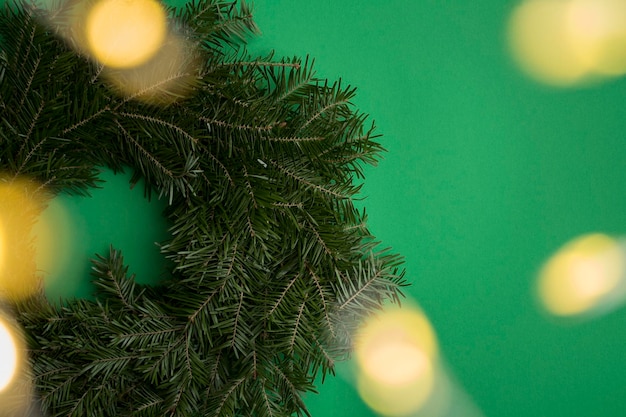 Composición navideña con anillo o corona navideña y guirnalda brillante en el fondo verde Copiar espacio