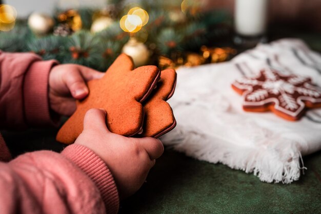 Composición navideña. Un árbol de Navidad decorado con juguetes y una guirnalda y pan de jengibre. Pan de jengibre en manos de un niño. Foto de alta calidad