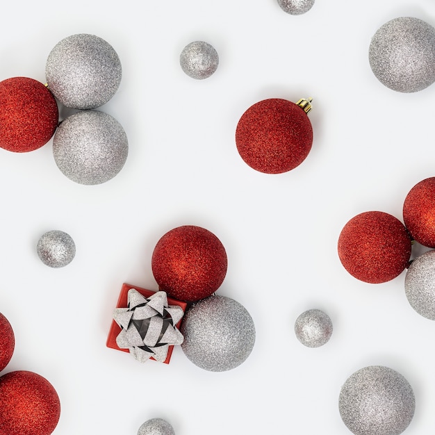 Composición navideña con bolas navideñas plateadas y rojas y caja de regalo con sorpresa en blanco