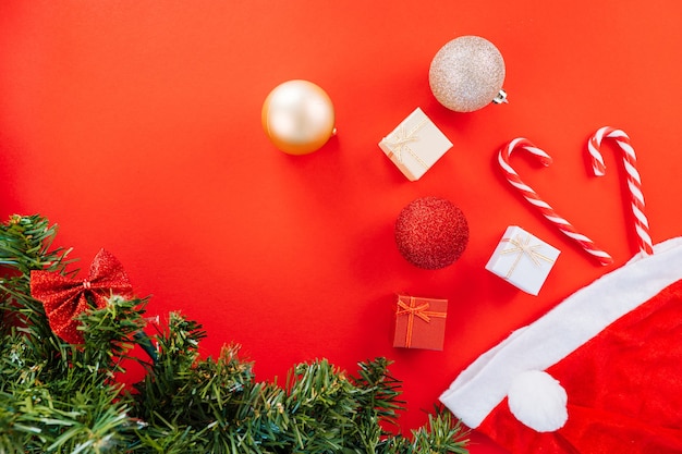 Composición navideña. Caja de regalo, ramas de abeto, caramelos de Navidad, adornos festivos rojos sobre fondo rojo. Copie el espacio.