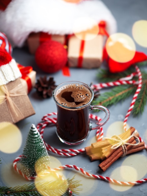 Composición navideña con cajas de regalo con gorro de Papá Noel y un vaso de café