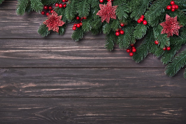 Composición navideña clásica con ramas de abeto flor de pascua y bayas de acebo sobre un fondo de madera