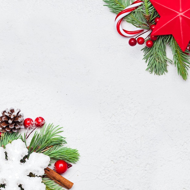 Composición navideña Estrellas rojas bayas de acebo copo de nieve y rama de abeto verde sobre fondo blanco Vista superior plana de Navidad con espacio de copia