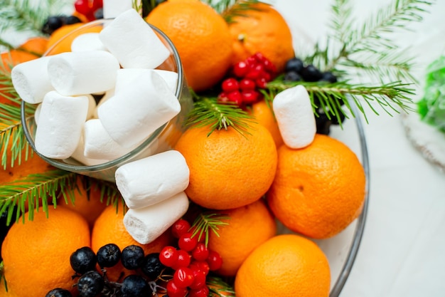 Composición navideña de mandarinas y ramitas de abeto con bayas en la mesa festiva