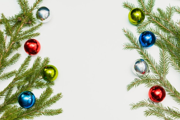 Composición navideña con marco vacío de bolas de colores y ramas de abeto. ornamento, decoraciones de año nuevo sobre fondo blanco. Plantilla de tarjeta de saludos de maqueta con espacio de copia, plana, vista superior.