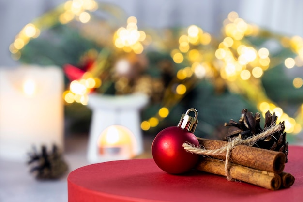 Composición navideña con palitos de canela de bola roja y velas de cono de abeto rama de abeto Decoraciones navideñas y luces bokeh Tarjetas de felicitación de Feliz Navidad y Año Nuevo Ambiente mágico