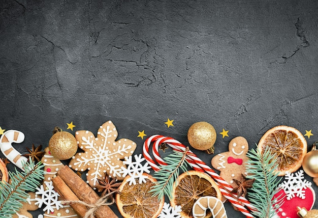 Composición navideña de pan de jengibre, canela, bastón de caramelo, confeti de naranja y ramitas de abeto