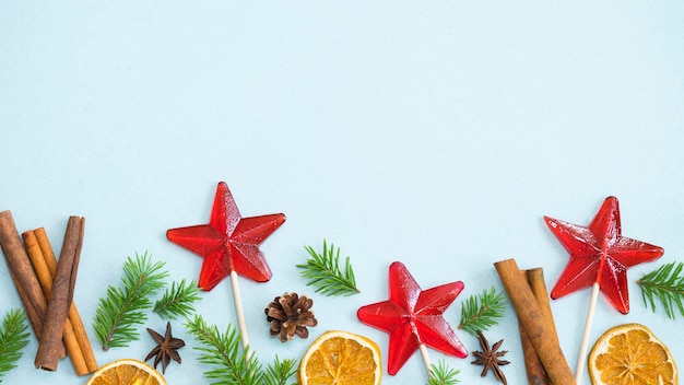 Composición navideña de piruletas, palitos de canela, anís estrellado, naranja seca y ramas de abeto