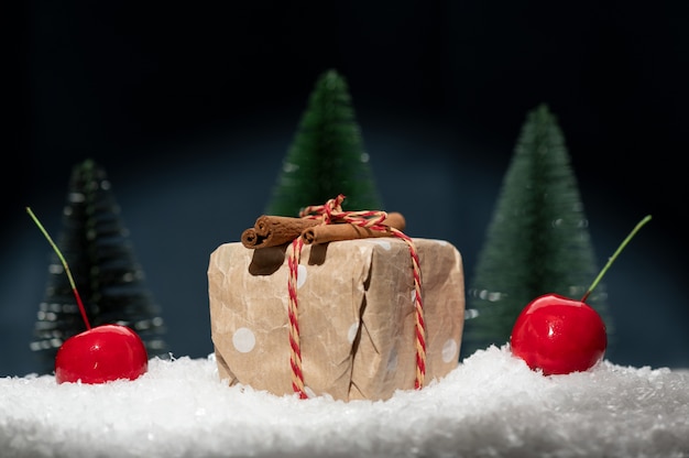 Composición navideña que consiste en un regalo tirado en la nieve y manzanas rojas