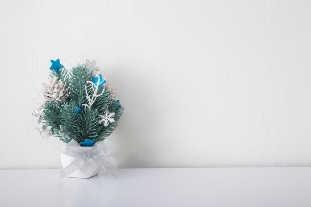 Composición navideña con ramas de abeto y adornos en interior blanco