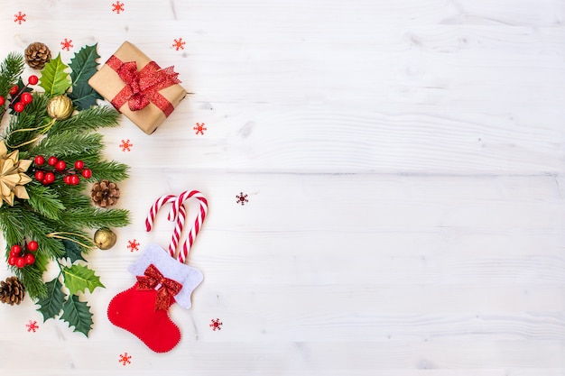 Composición navideña con ramas de abeto, dulces, regalos, piñas y estrellas en madera clara