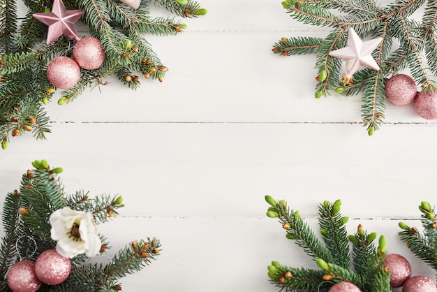 Composición navideña. Ramas de abeto en la pared blanca de madera Endecha plana, vista superior, espacio de copia. Bodegón navideño. Marco de Navidad hecho de ramas de abeto y juguetes de color rosa. Feliz año nuevo