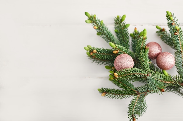 Composición navideña. Ramas de abeto en la pared blanca de madera Endecha plana, vista superior, espacio de copia. Bodegón navideño. Marco de Navidad hecho de ramas de abeto y juguetes de color rosa. Feliz año nuevo