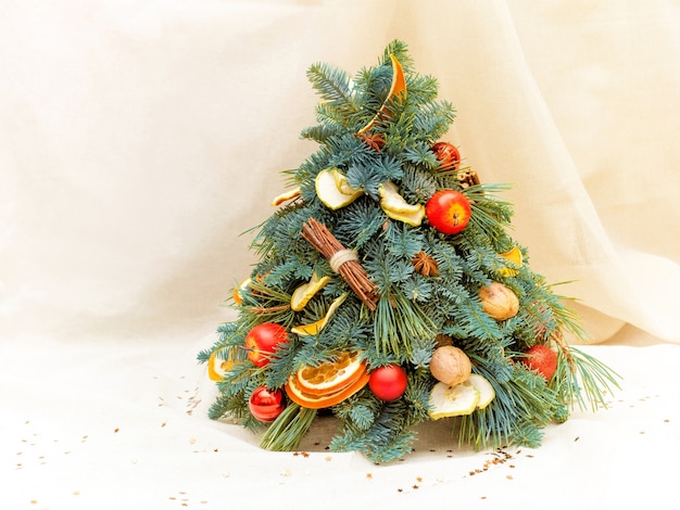 Composición navideña de ramas de abeto, rodajas de naranja y manzana, nueces, anís y bolas. Fotografía de cerca. Sobre fondo beige
