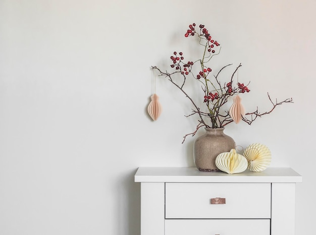 Composición navideña con ramas y adornos navideños artesanales en una mesa blanca de madera